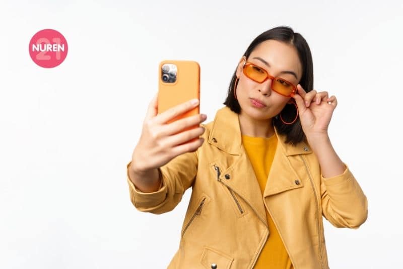 woman in orange jacket and orange shirt with orange sunglasses retro look taking selfie 