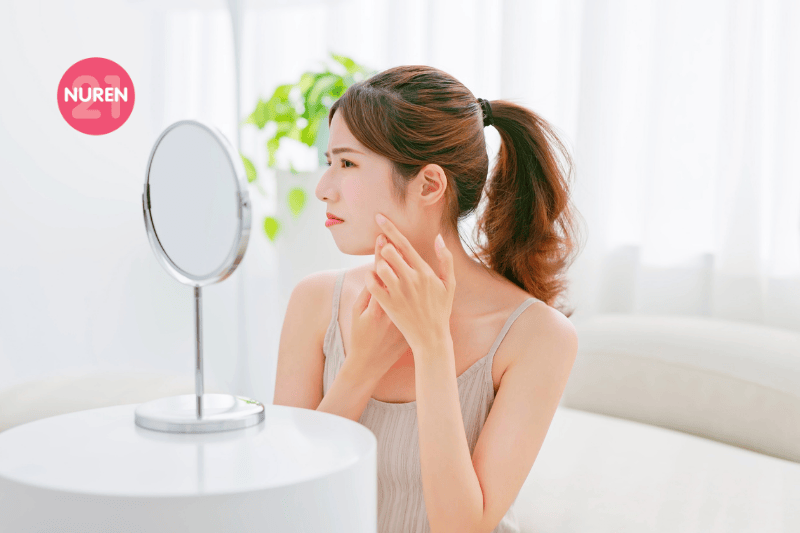 woman looking into mirror unhappy with skin 